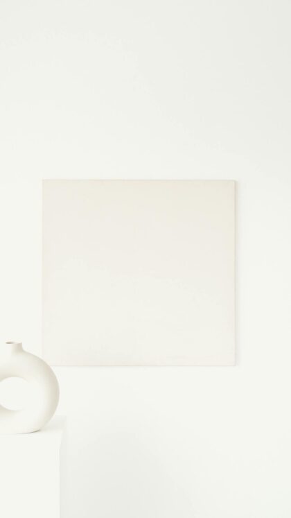 A minimalist interior featuring abstract art and a modern vase on a white surface.